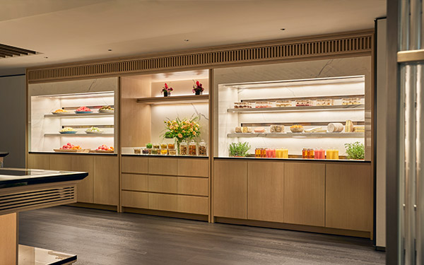 A modern, well-lit display cabinet showcases assorted pastries and drinks inside a clean, upscale café or bakery setting.